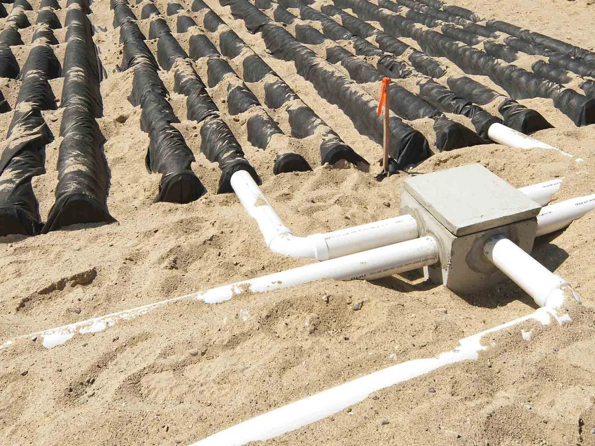A concrete distribution box and pipes set in a new drain field bed