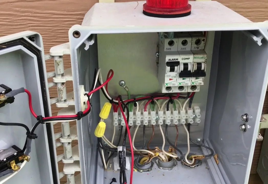 A septic control panel with a red alarm light on the cover