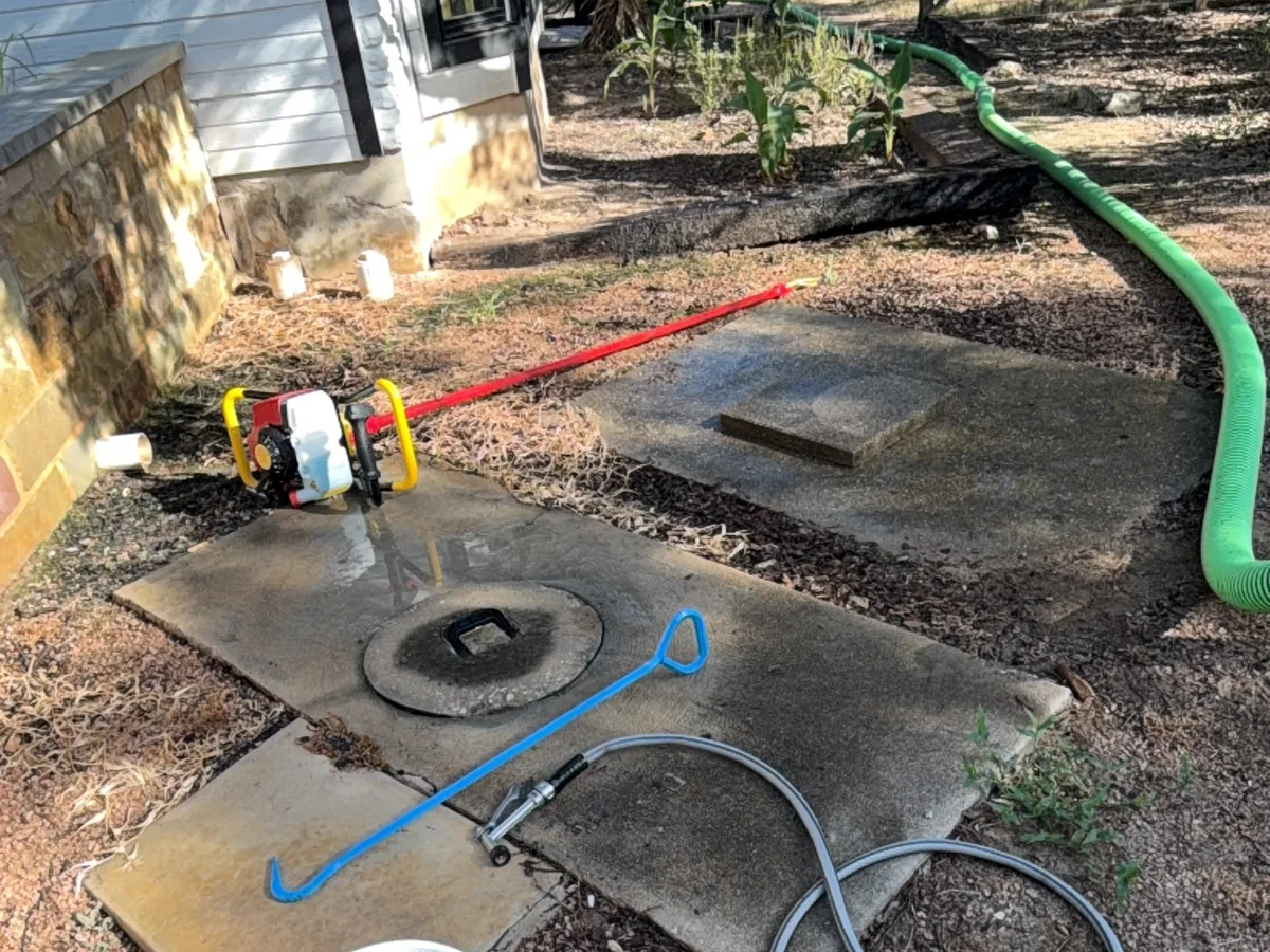 Concrete septic tank lids uncovered beside a home with access tools laid out