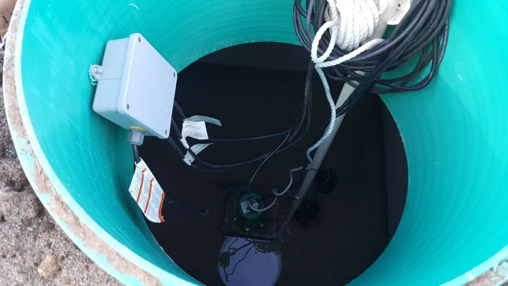A pump and float switch inside an open septic pump tank riser