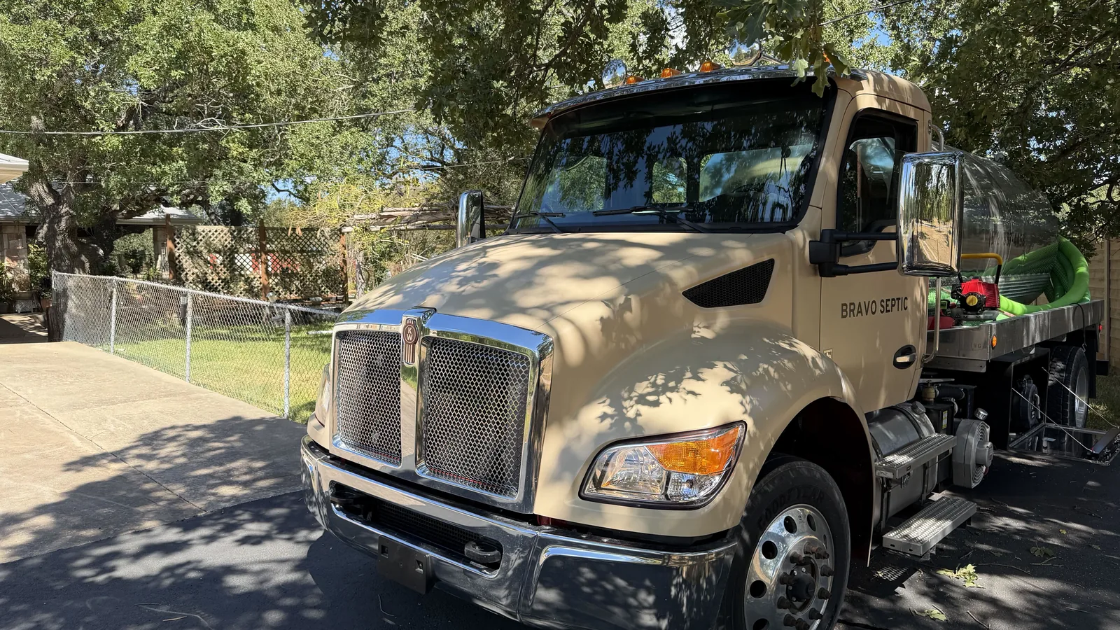 The Bravo Septic pump truck parked on a gravel drive under live oaks