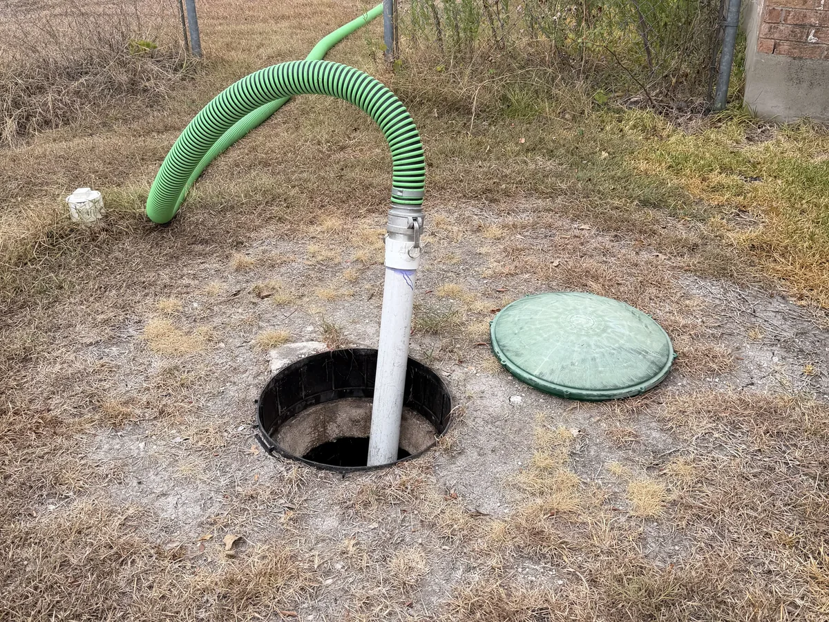 A septic tank lid opened with the suction hose lowered into the tank